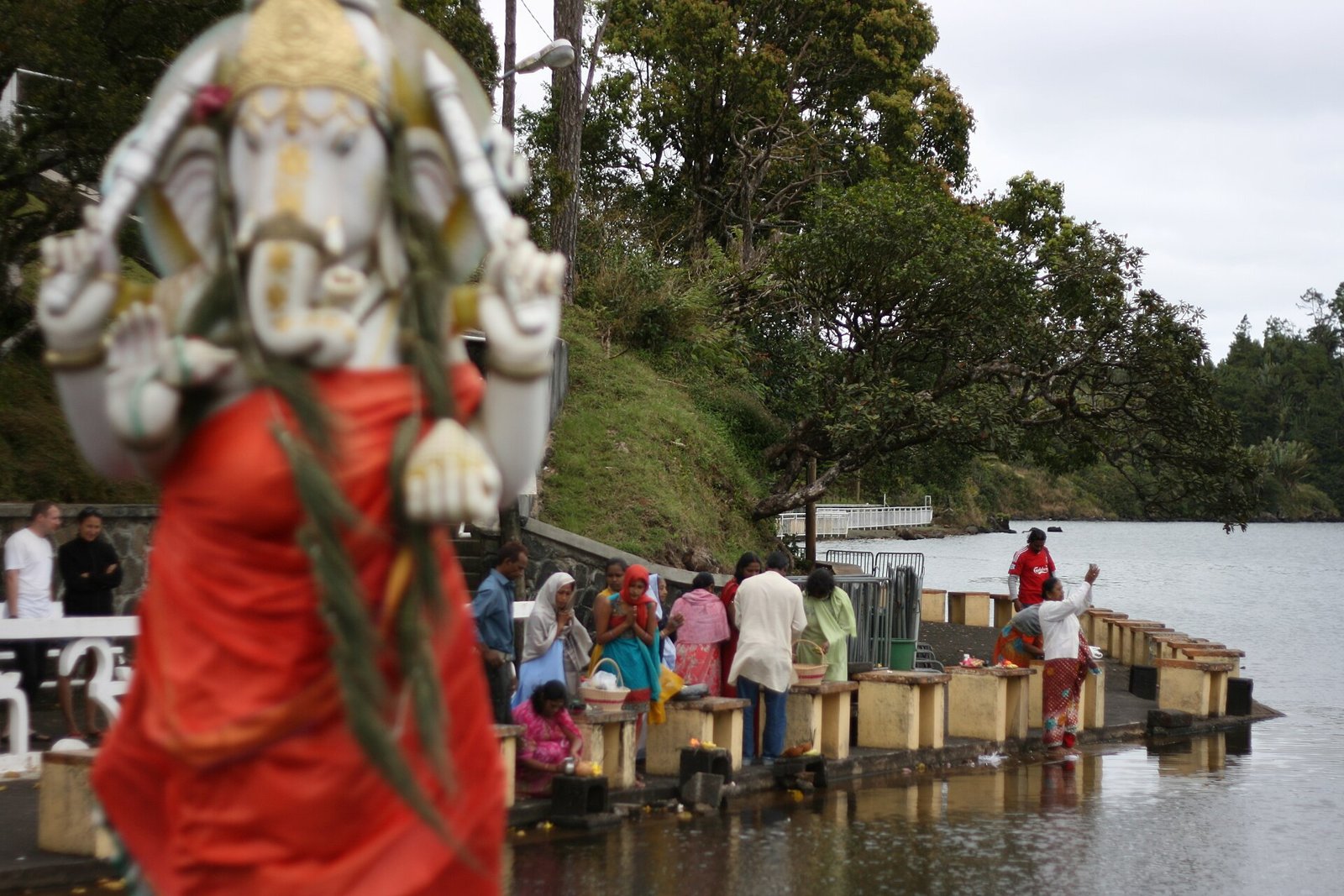Ganesha-Statue mit betenden Gläubigen am Wasser