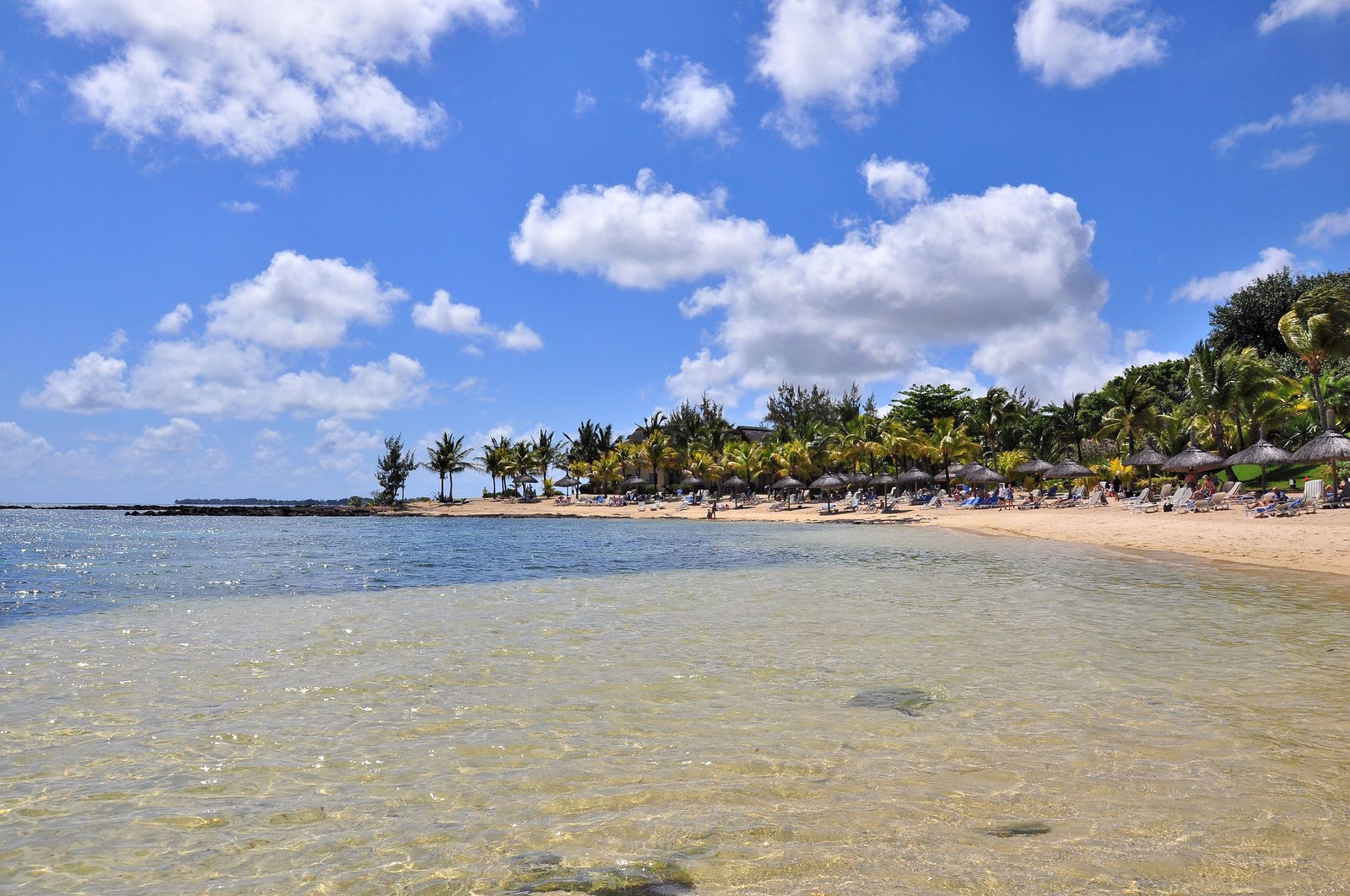 Strand mit Palmen, Sonnenschirmen und klarem, flachem Wasser bei Mont Choisy