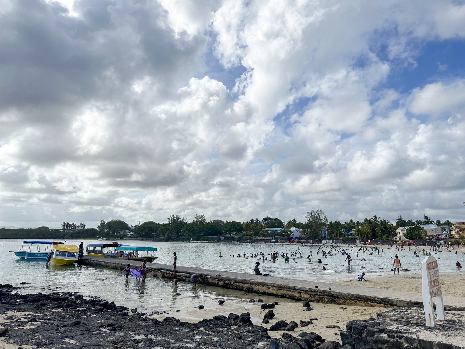 Ausflugsboote und Badegäste am Strand von Blue Bay