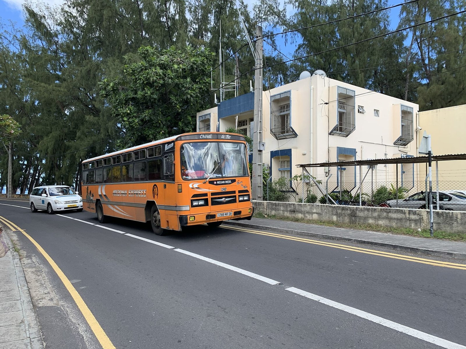 Ein orangefarbener Linienbus und ein Taxi in Flic en Flac